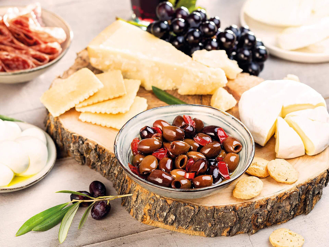 Board with cheeses and spicy olives